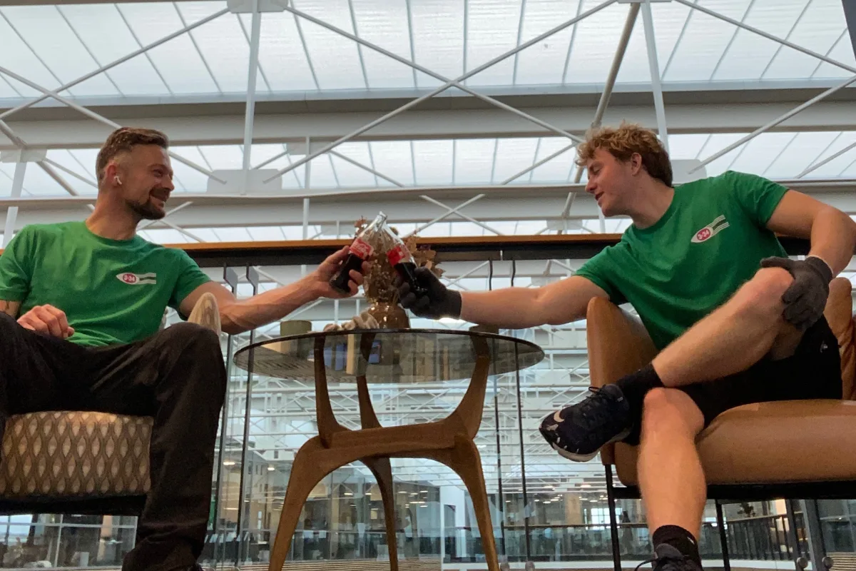 To unge flyttefolk nyder en pause med cola i et moderne kontor i København.
