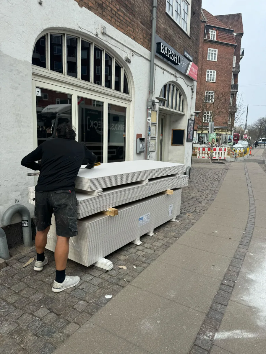 70 gipsplader klar til at blive båret op til et byggeprojekt i København. Optimal løsning til effektiv opbæring af gipsplader til dit hjem.