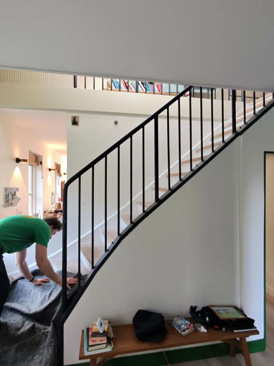 Flytning af en seng op ad en snæver trappe til soveværelset i København, omhyggeligt håndteret med tæpper for at undgå skader.