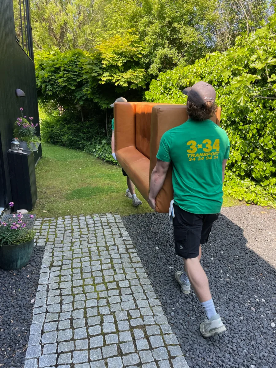 Stor sofa manøvreres gennem en smal opgang under opbæring i København S