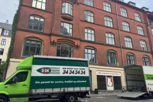 To 3×34-flyttevogne parkeret foran en etageejendom på Frederiksberg