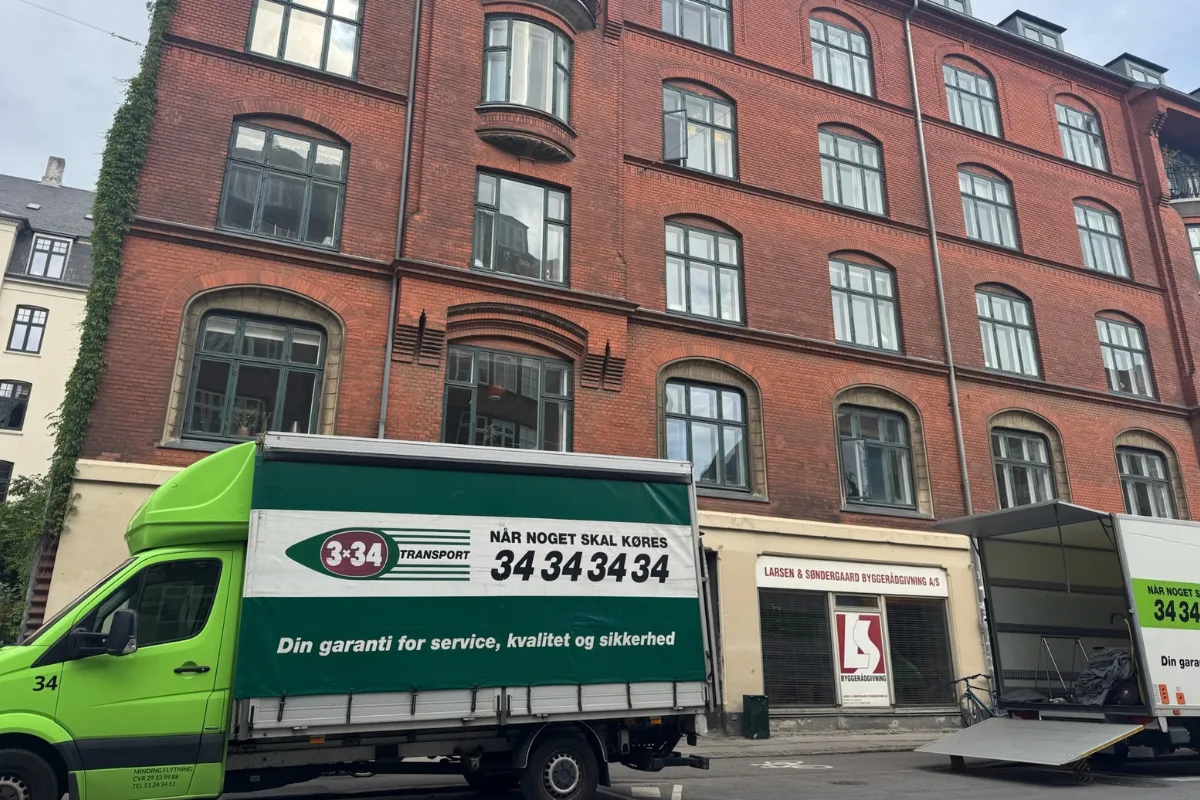 To 3×34-flyttevogne parkeret foran en etageejendom på Frederiksberg