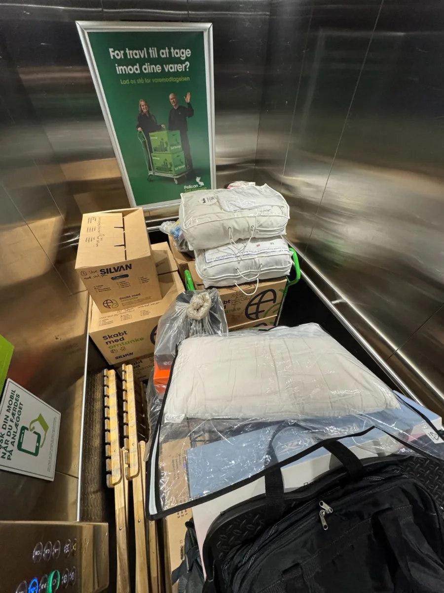 Flyttekasser, poser og indpakkede genstande står tæt pakket i en elevator.