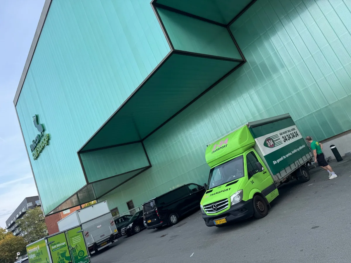 En 3x34 flyttevogn holder ved Pelican Self Storage i København NV, mens en flyttemand står ved bagsiden af vognen.