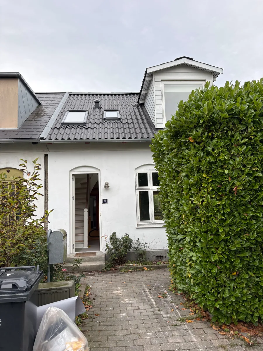 Et hus med åben hoveddør og synlig trappe indenfor.