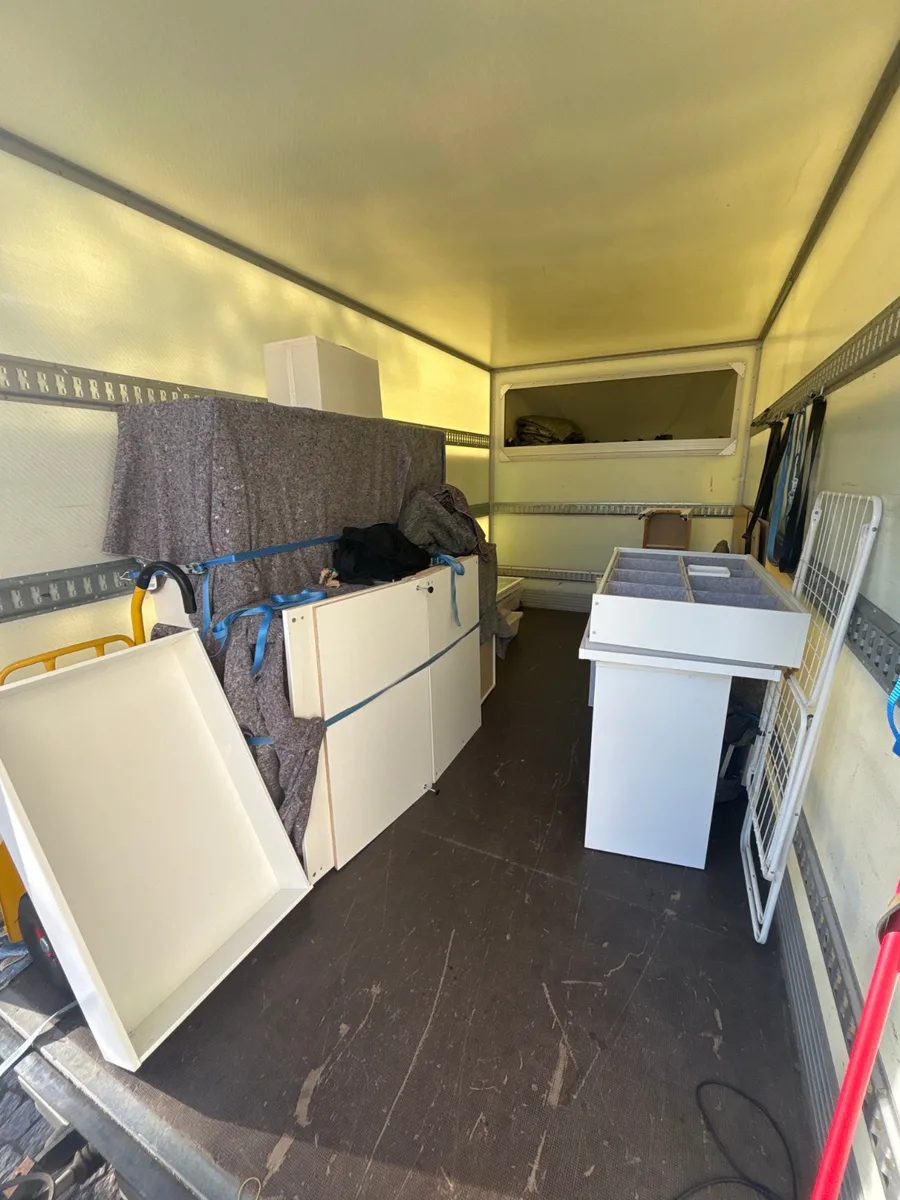 Et afmonteret ikea pax garderobe skab og andre møbeldele er surret fast i en flyttevogn.