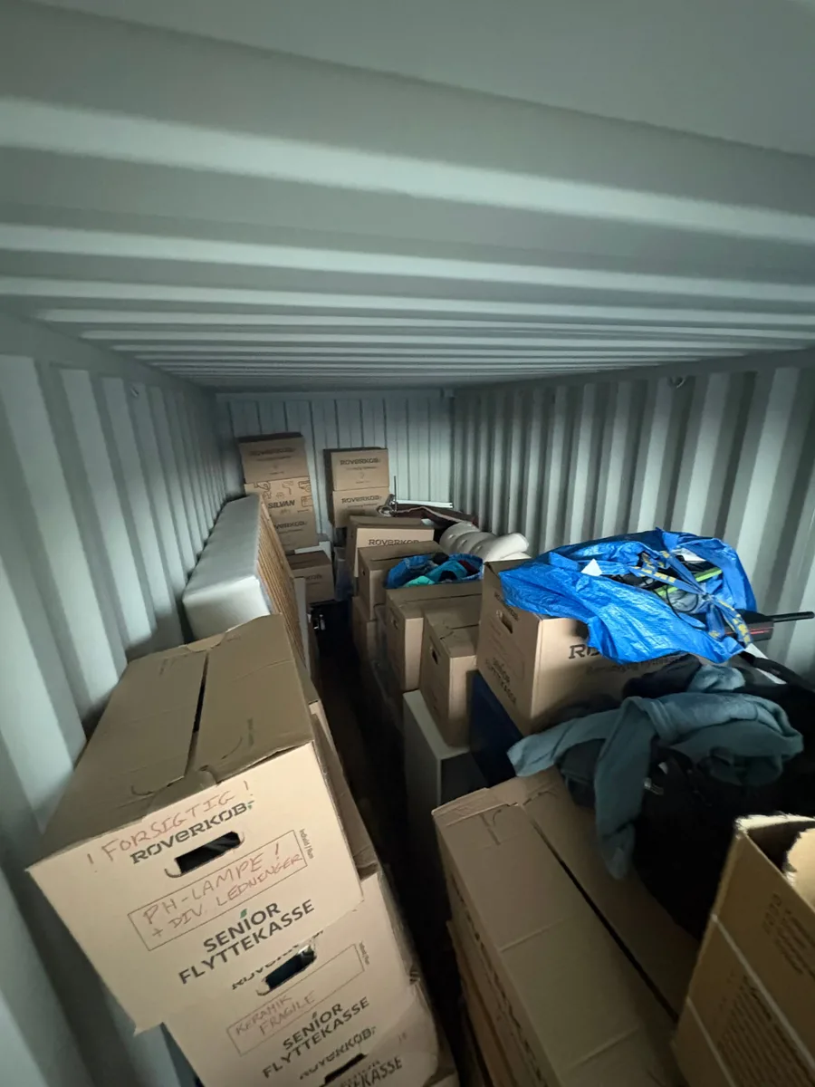 En container er fyldt tæt med flyttekasser, en madras og andre pakket genstande.