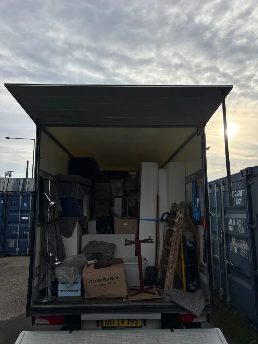 En container er fyldt med flyttelæs, blandt andet flyttekasser, en gulvlampe og indpakkede møbler.