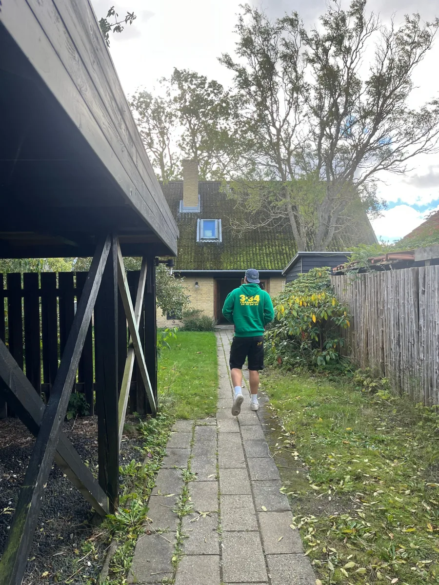 En flyttemand går ad en smal havesti mod et hus.
