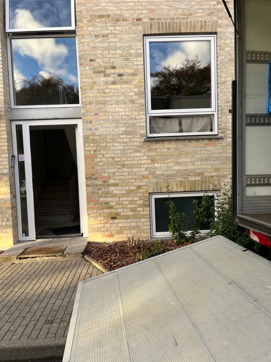En rampe ligger foran en åben opgang i en murstensbygning.